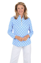 Woman wearing a blue floral patterned shirt on a white background.