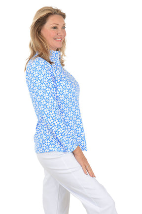 Woman wearing a blue floral patterned shirt on a white background. Side shot.