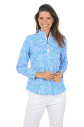 Woman wearing a blue patterned long-sleeve top on a white background. Side shot.