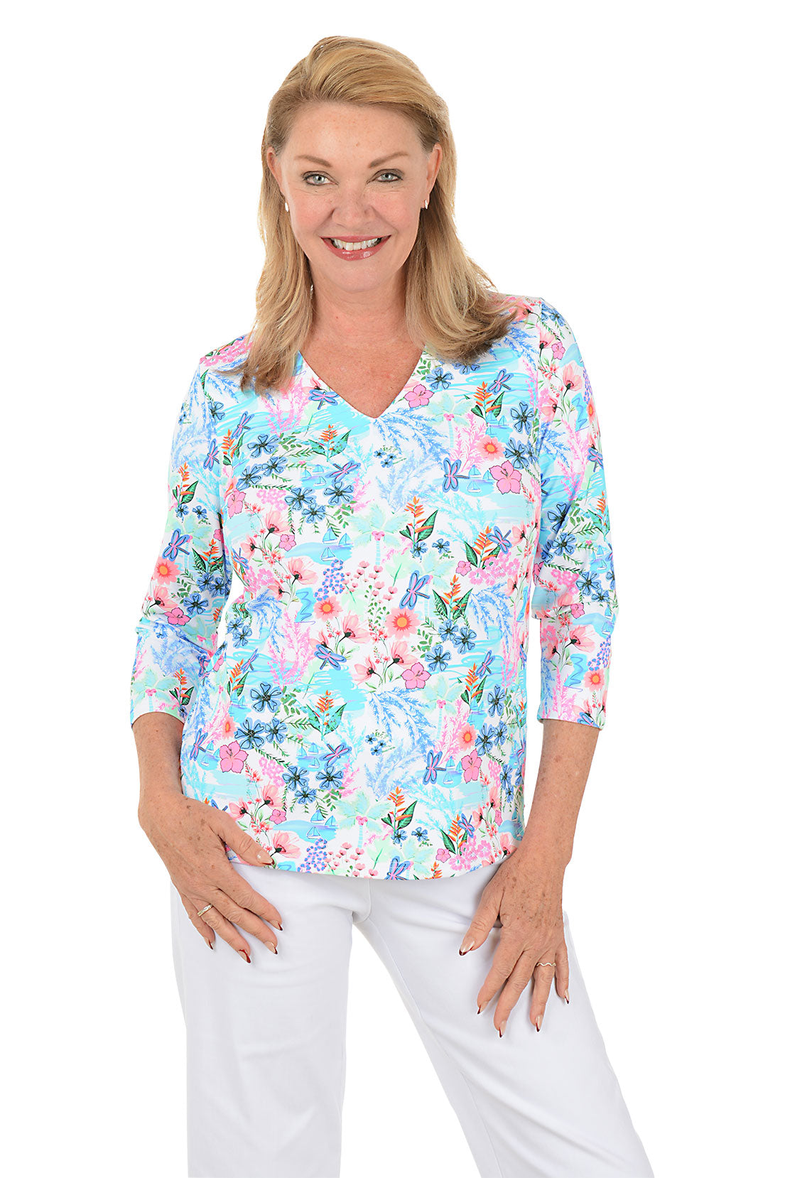 Woman wearing a floral blouse with white pants on a white background. Second front shot.