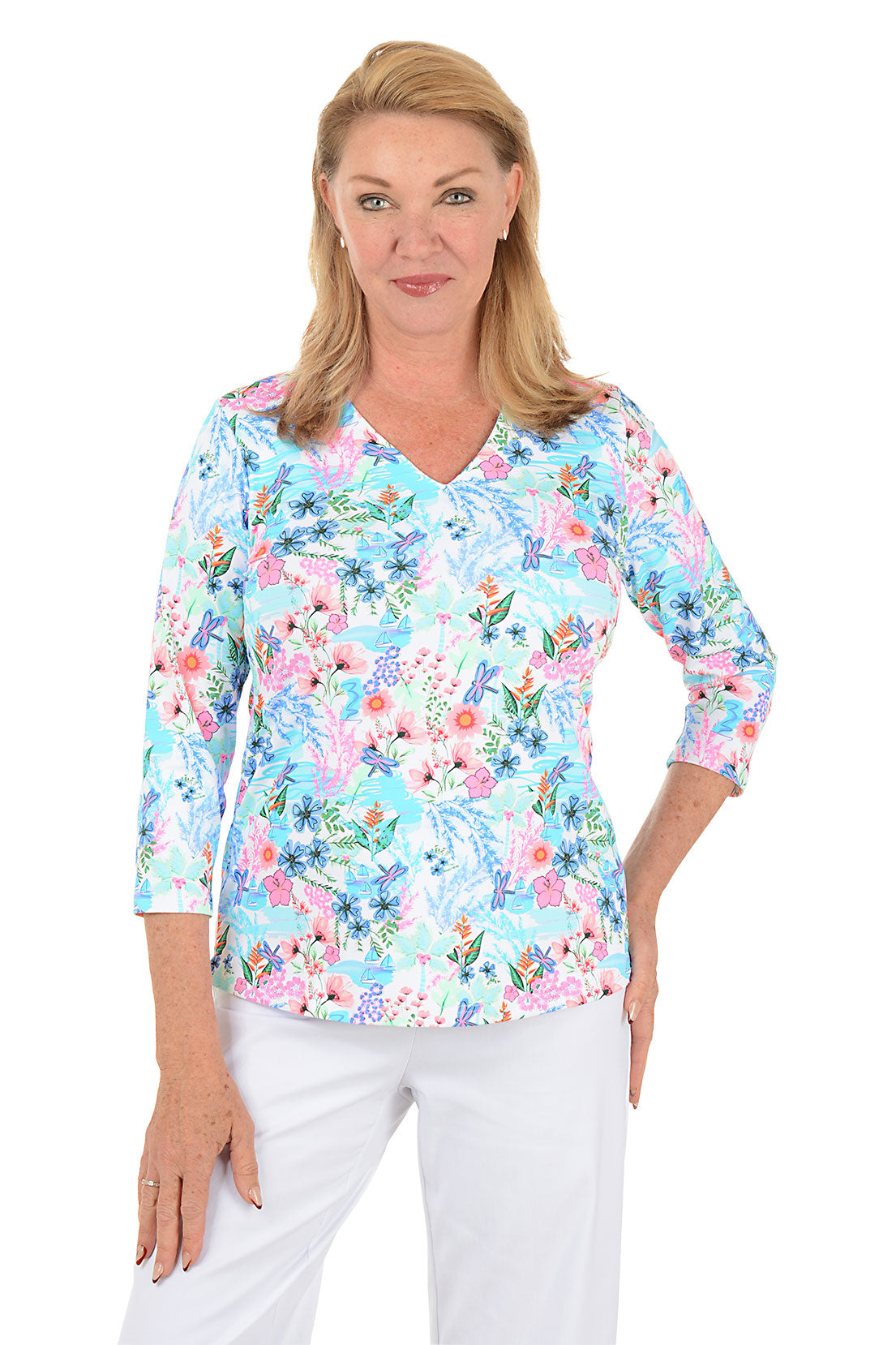 Woman wearing a floral blouse with white pants on a white background.