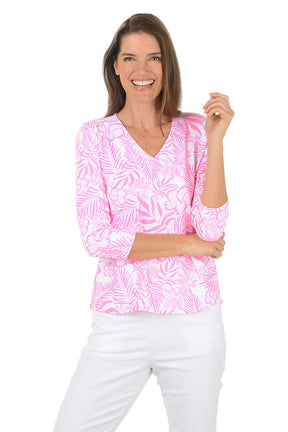 Woman wearing a pink and white patterned blouse with a white background.