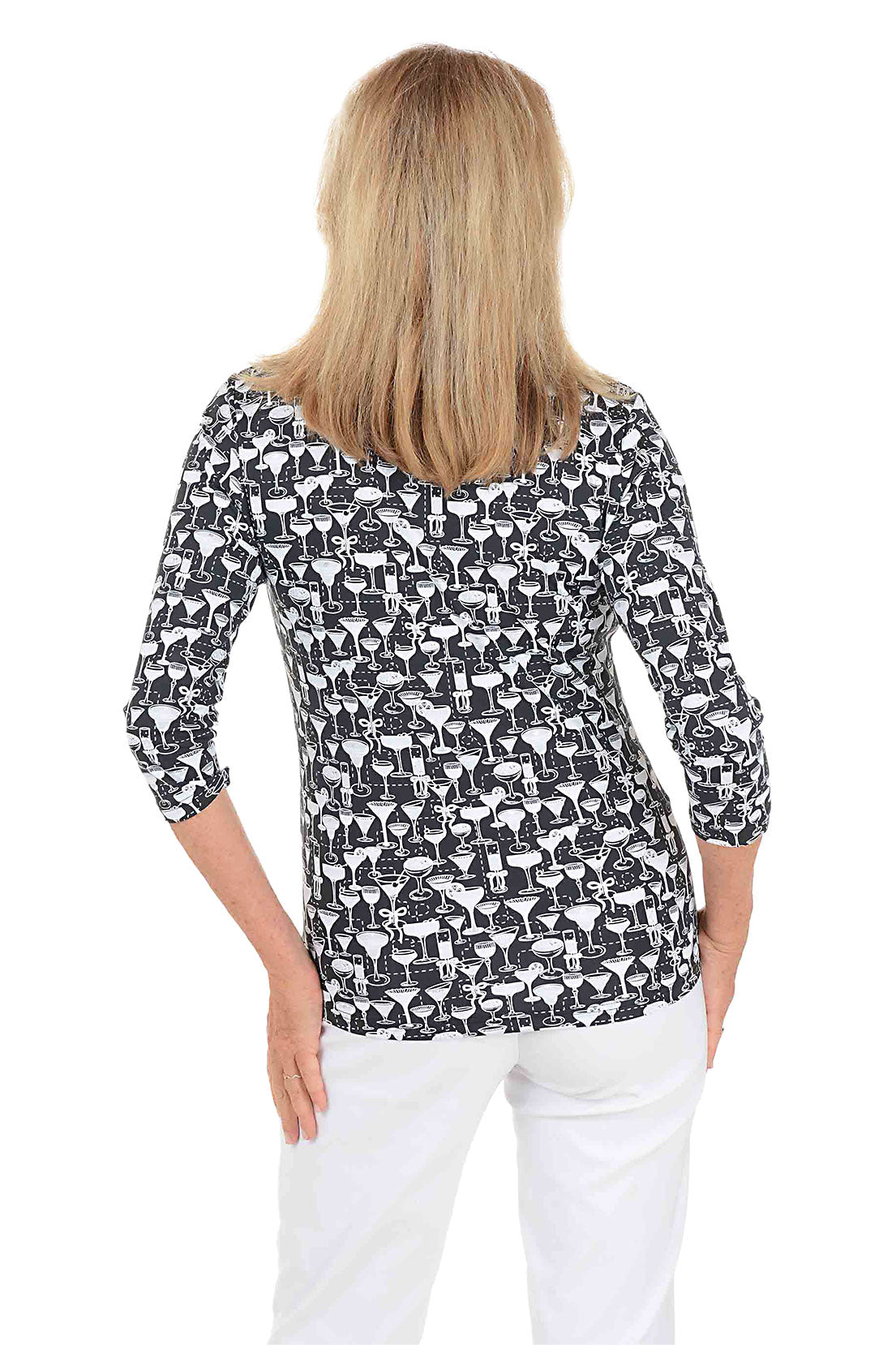 A woman wearing a black and white cocktail patterned v-neck 3/4 sleeve top with silver foil accents. Back shot.