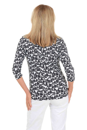A woman wearing a black and white cocktail patterned v-neck 3/4 sleeve top with silver foil accents. Back shot.
