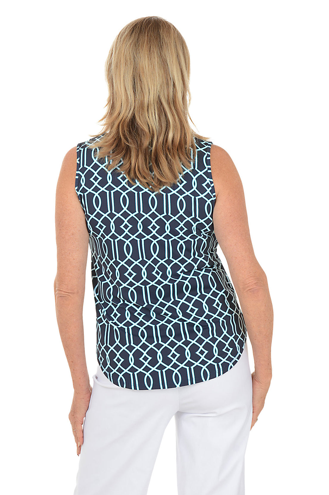 Woman wearing a sleeveless patterned top and white pants on a white background. Back shot.