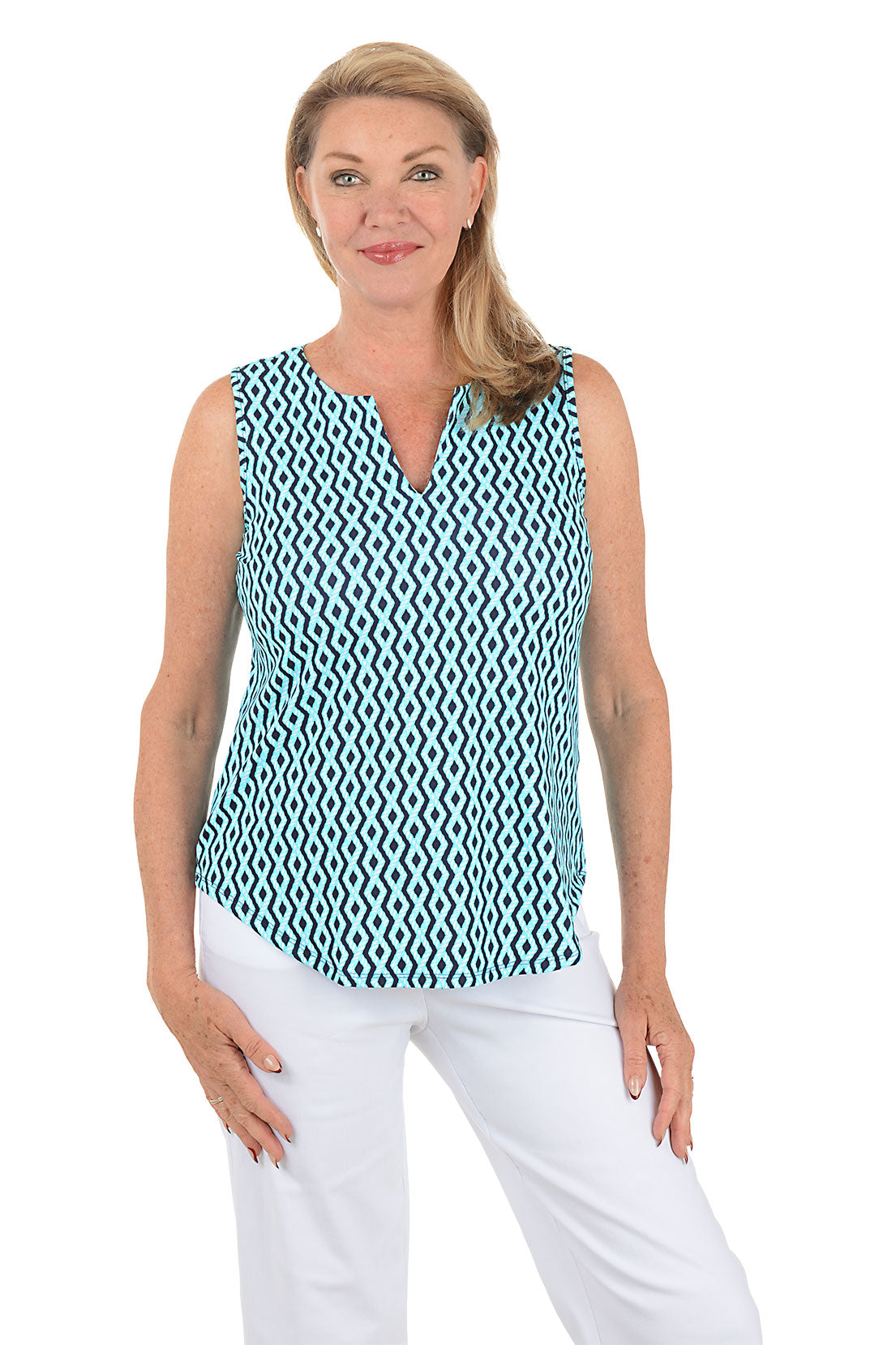 Woman wearing a sleeveless patterned top and white pants on a white background.