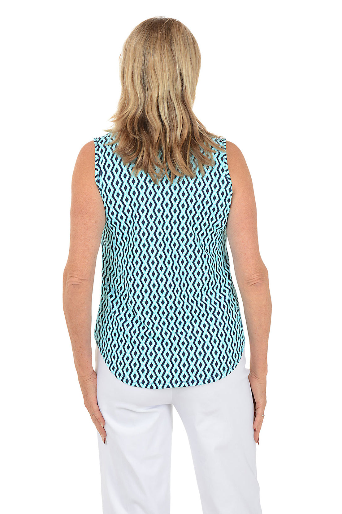 Woman wearing a sleeveless patterned top and white pants on a white background. Back shot.