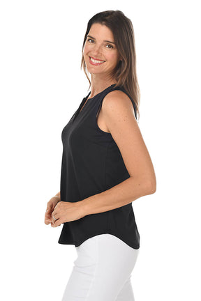 Woman wearing a black sleeveless top and white pants on a white background. Side shot.