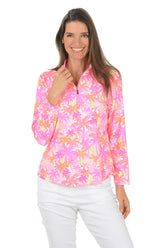 Woman wearing a colorful floral long-sleeve shirt on a white background.