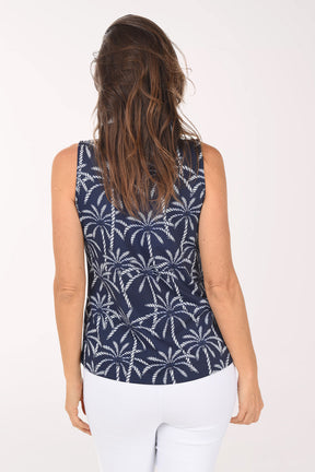 Woman wearing a navy sleeveless top with white palm tree pattern on a white background