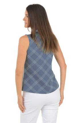 Woman wearing a blue patterned sleeveless top and white pants on a white background. Back shot.
