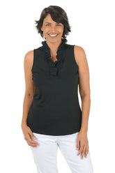 Woman wearing a black sleeveless top with ruffles and white pants on a white background.
