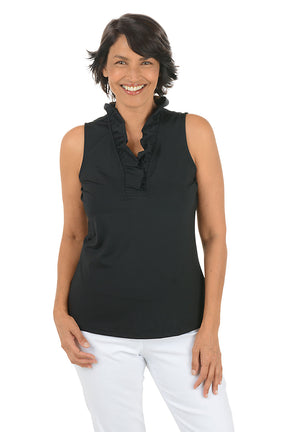 Woman wearing a black sleeveless top with ruffles and white pants on a white background.