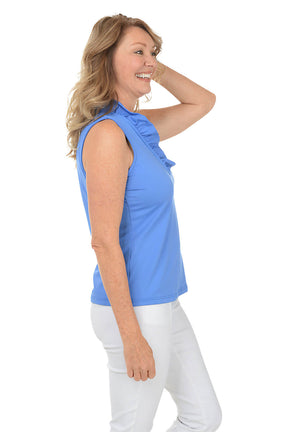 Woman wearing a blue sleeveless top and white pants on a white background