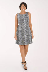 A woman modeling a sleeveless fit-and-flare dress with a black and white leopard print pattern, paired with black strappy heels, against a plain white studio background.