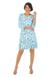 Woman wearing a blue floral dress on a white background.