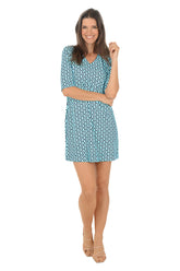 Woman wearing a blue patterned dress on a white background.
