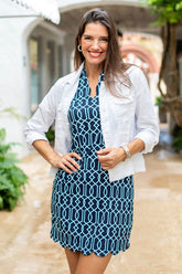 Woman wearing a blue patterned dress with a white jacket outdoors.