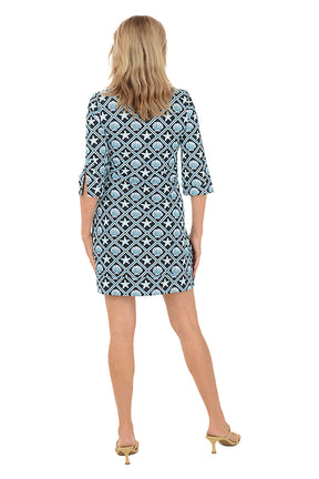 Woman wearing a patterned dress on a white background. Back shot.