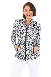 A woman wearing a black and white leopard-spotted zip front jacket and white pants in front of a white background.
