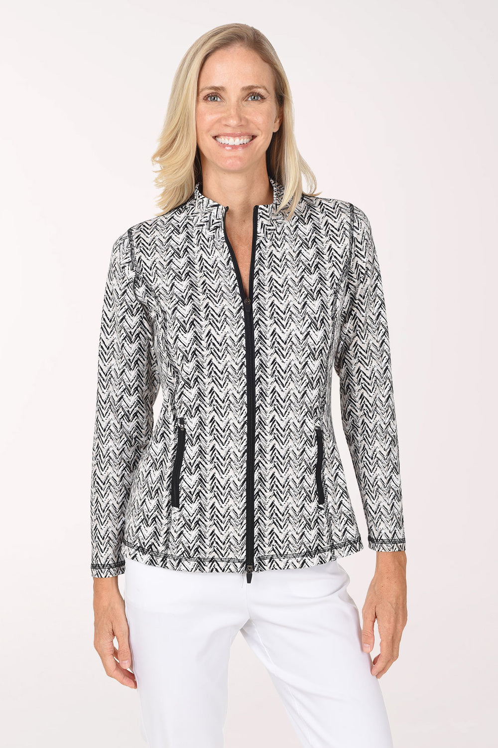 Front view of a model wearing the Anthony's Resort Wear Neutral Chevron UPF50+ Athletic Zip Jacket in a black and white brushstroke chevron print, with a black front zipper, black zip hip pockets and mock neck, worn with white pants.