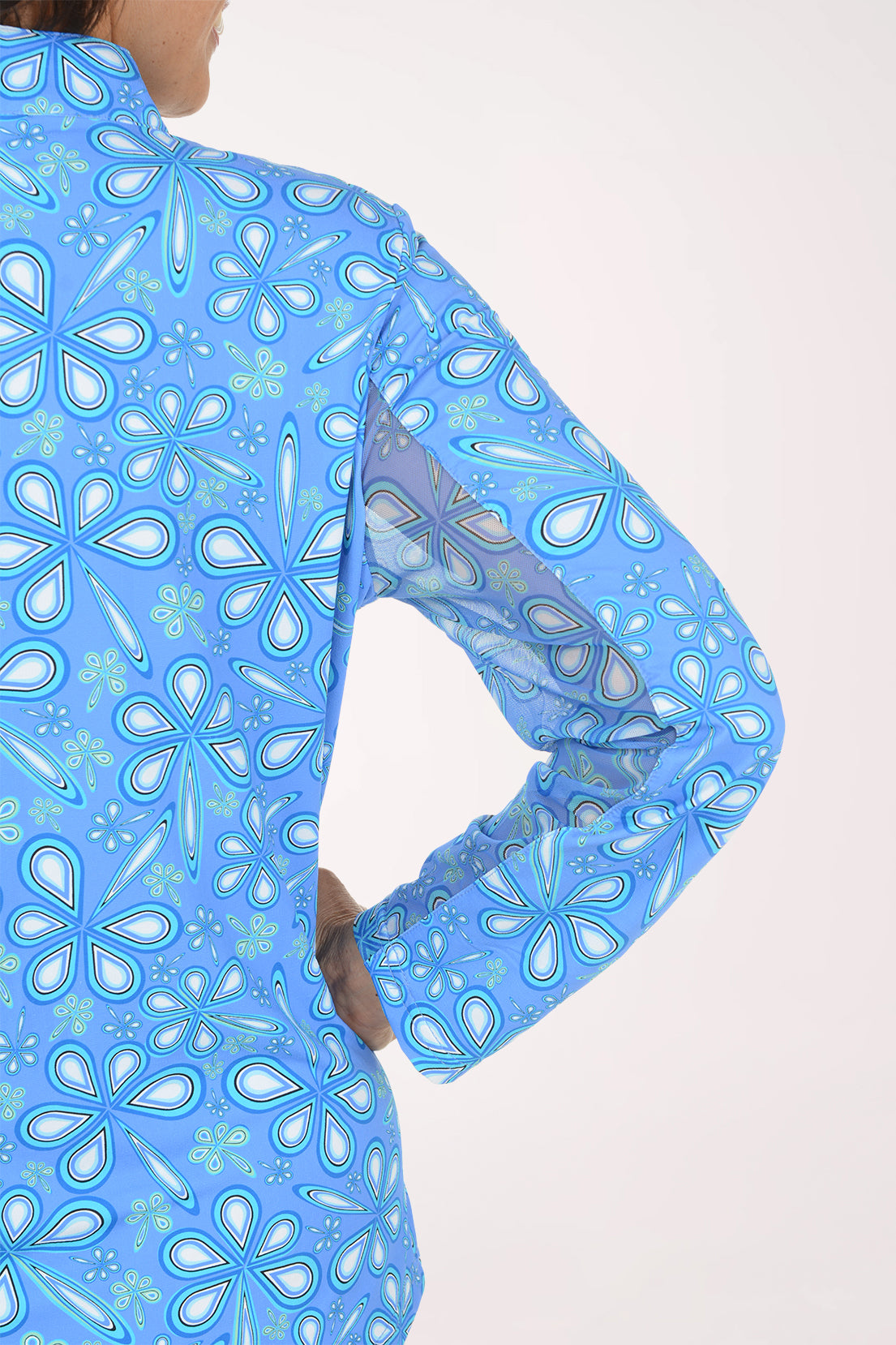 A close-up of a person wearing a light blue long-sleeve top with a white and light blue floral pattern, shown from the back against a plain light background.