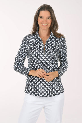 Woman wearing a patterned long-sleeve shirt and white pants on a light pink background