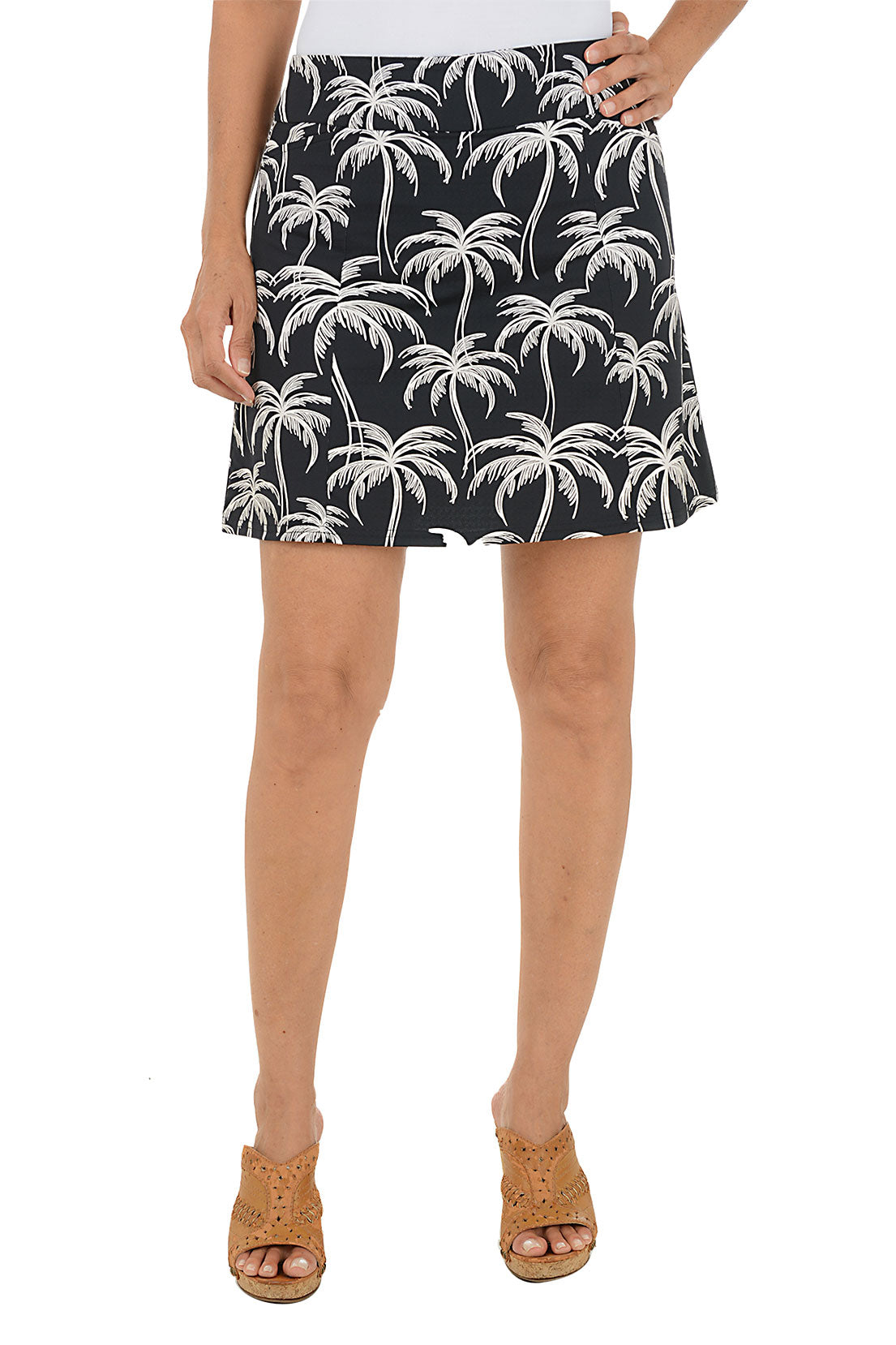 Person wearing a black skirt with white palm tree pattern on a white background.