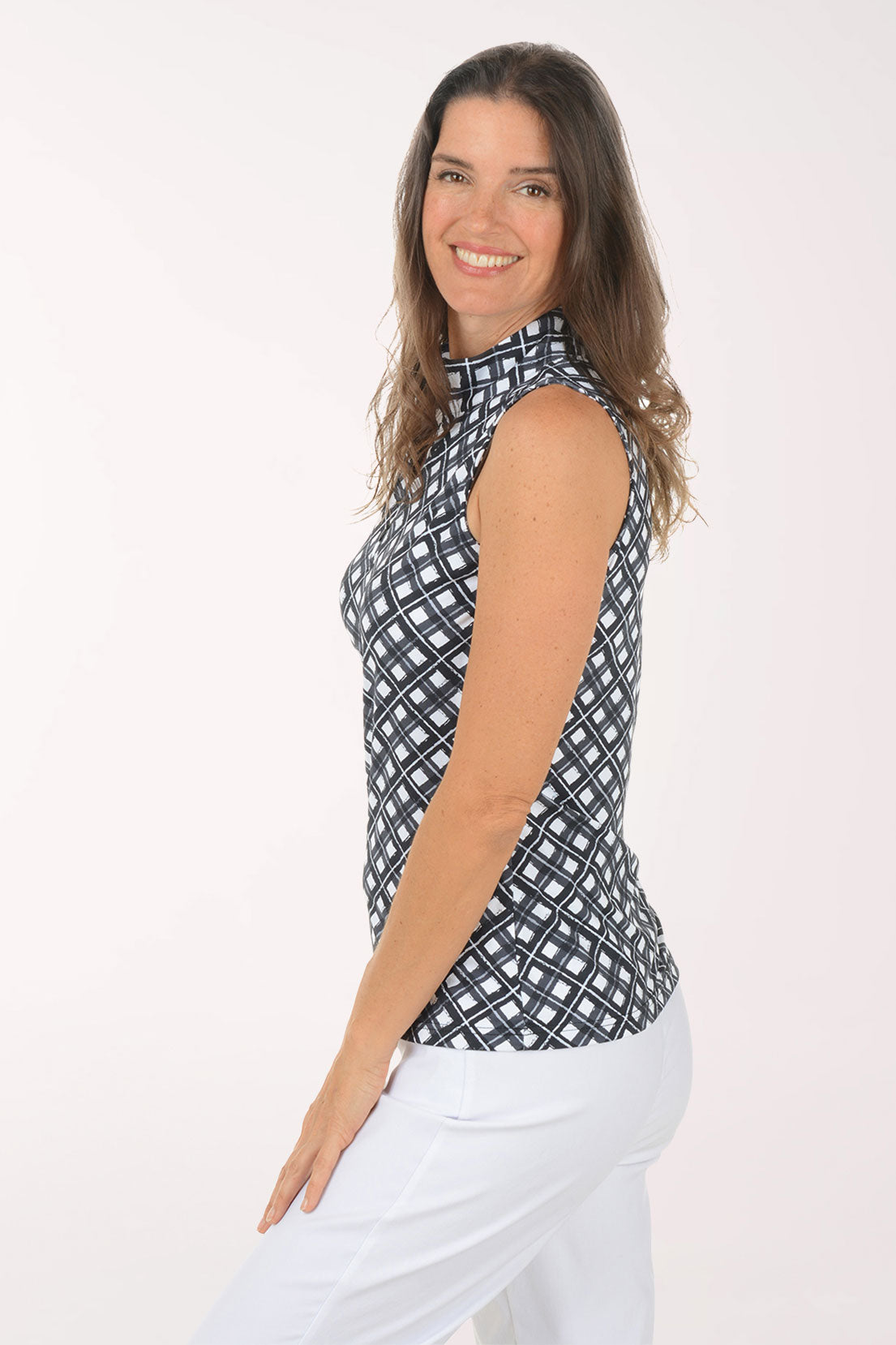 Woman wearing a black and white sleeveless patterned top against a white background