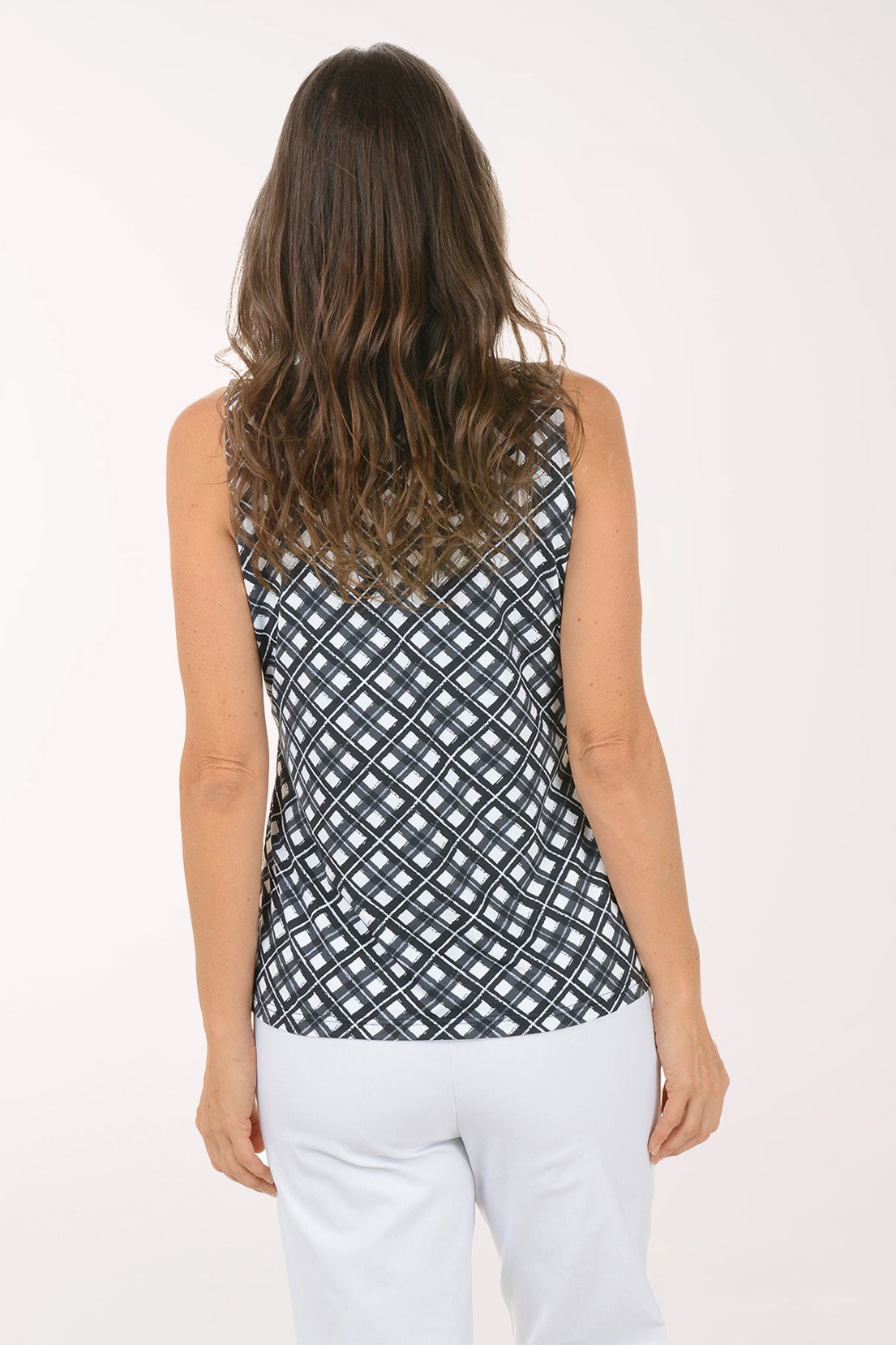 Woman wearing a black and white sleeveless patterned top against a white background