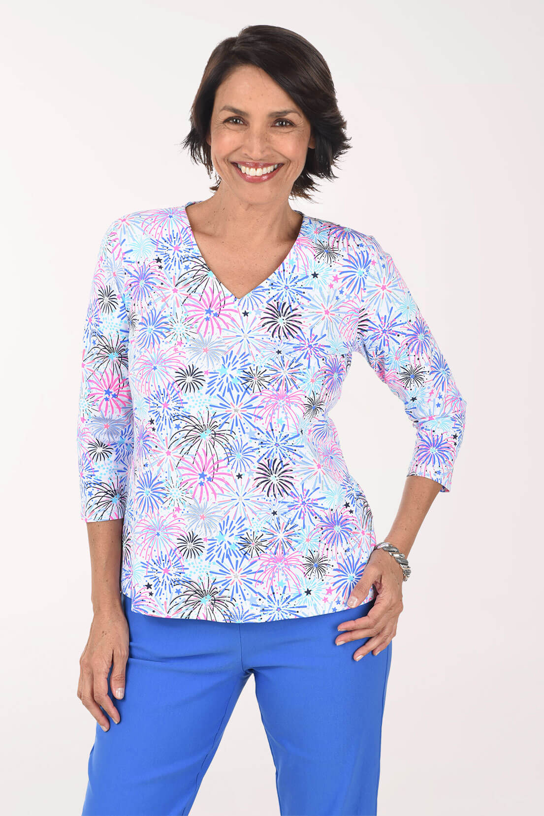 Woman wearing a colorful floral blouse and blue pants on a white background