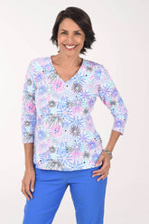 Woman wearing a colorful floral blouse and blue pants on a white background