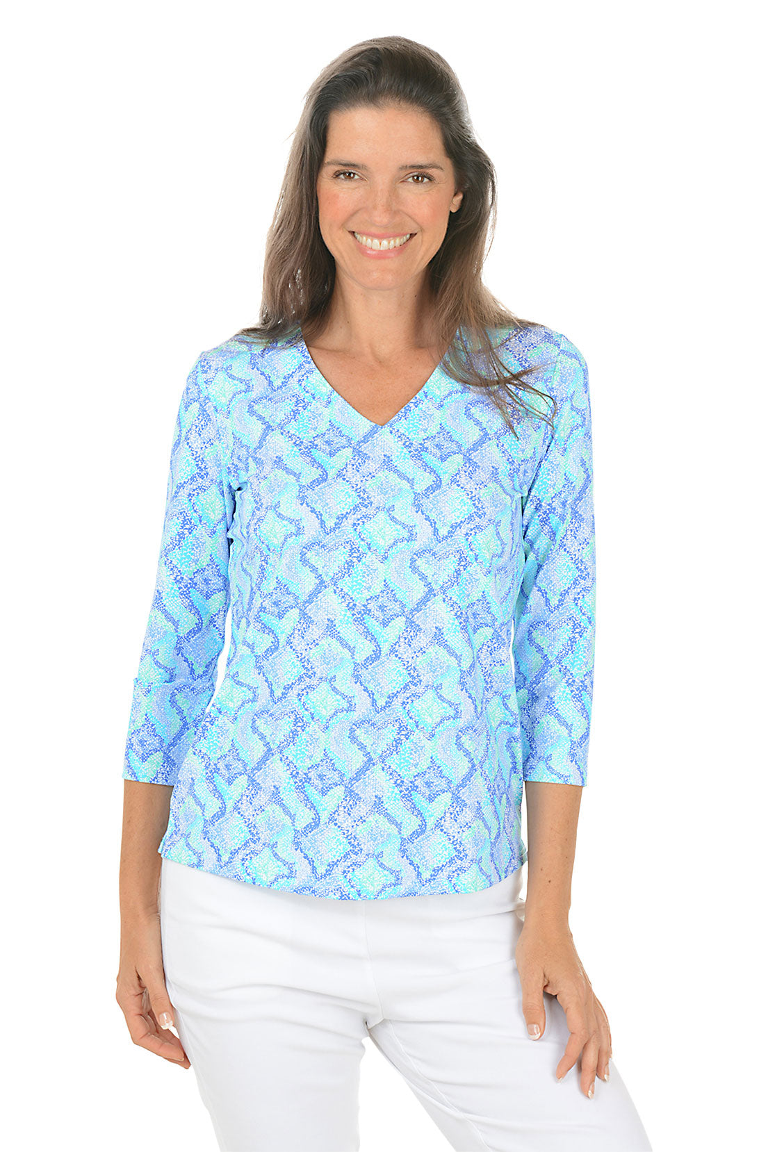 Woman wearing a blue patterned top and white pants on a white background.