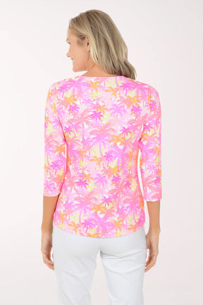 Woman wearing a colorful floral blouse with white pants on a white background