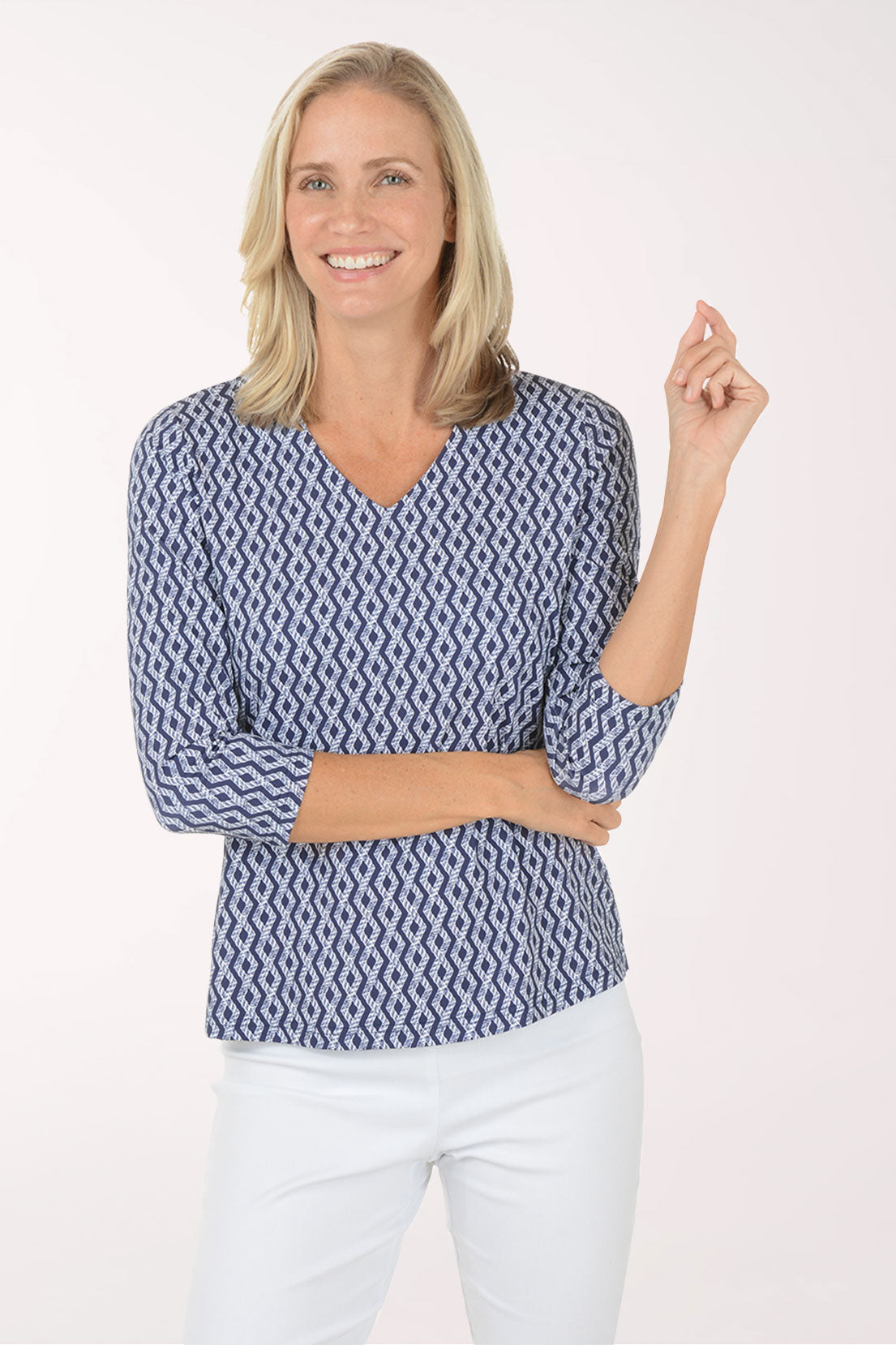 Woman wearing a blue patterned blouse and white pants on a white background