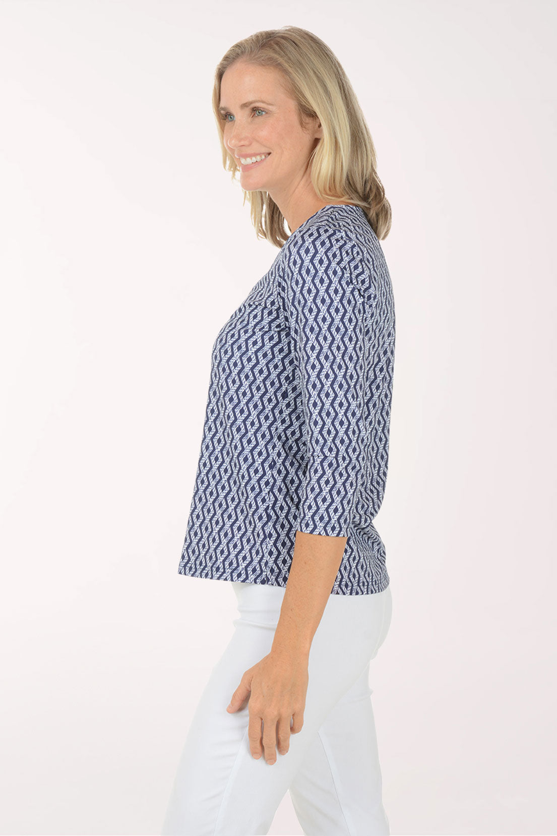 Woman wearing a blue patterned blouse and white pants on a white background