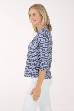 Woman wearing a blue patterned blouse and white pants on a white background