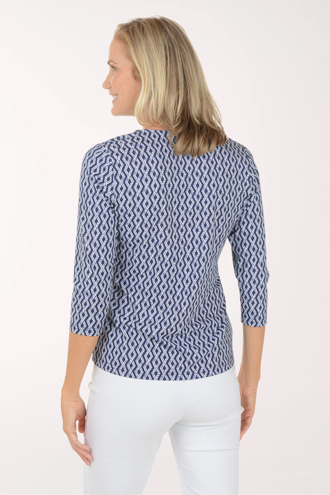 Woman wearing a blue patterned blouse and white pants on a white background