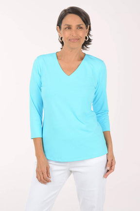Woman wearing a light blue top and white pants on a white background