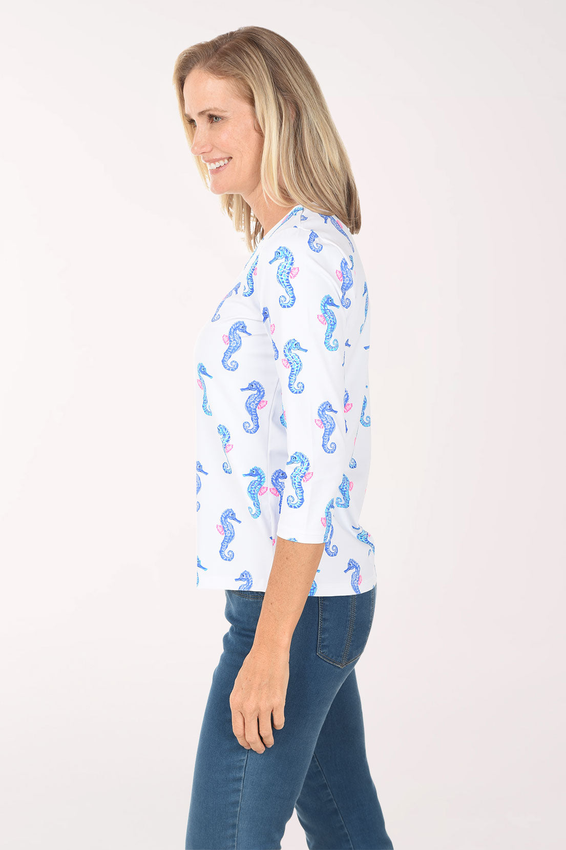 Woman wearing a white blouse with blue seahorse pattern on a white background