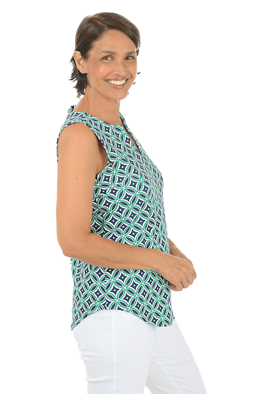 Woman wearing a navy and green patterned sleeveless top on a white background. Side shot.