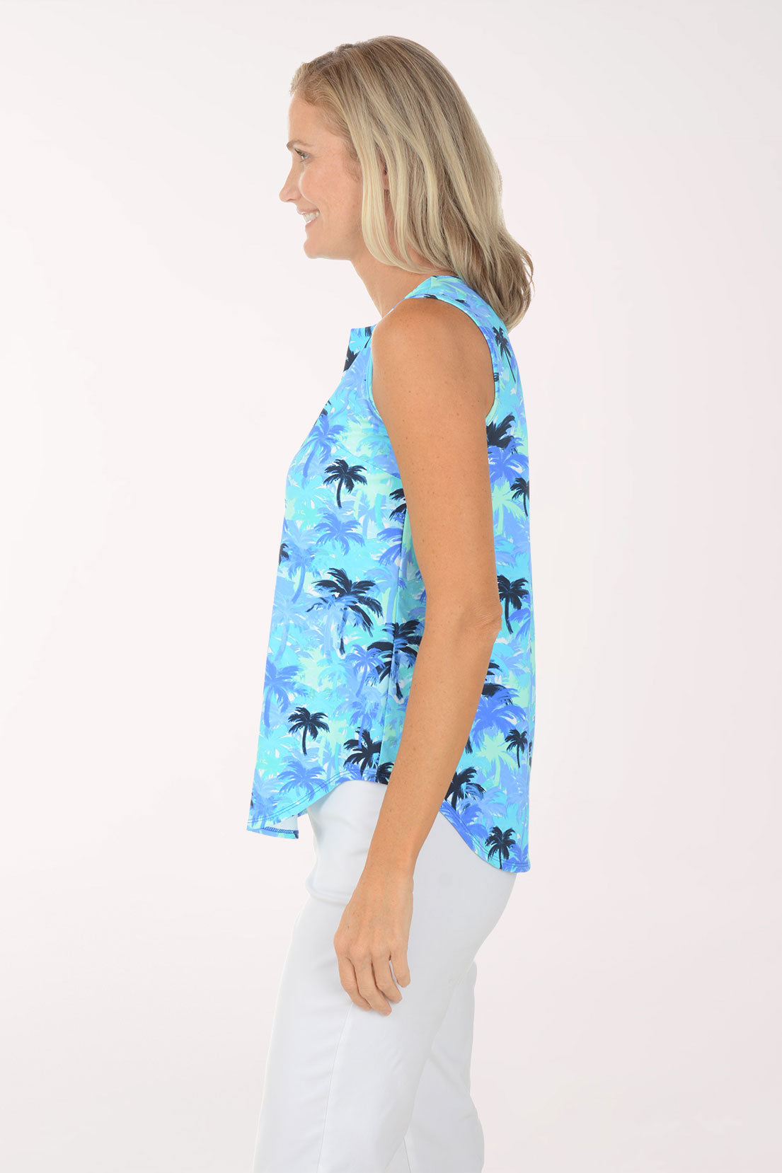 Woman wearing a sleeveless blue palm tree patterned top on a white background
