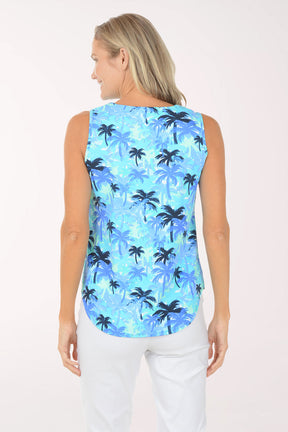 Woman wearing a sleeveless blue palm tree patterned top on a white background