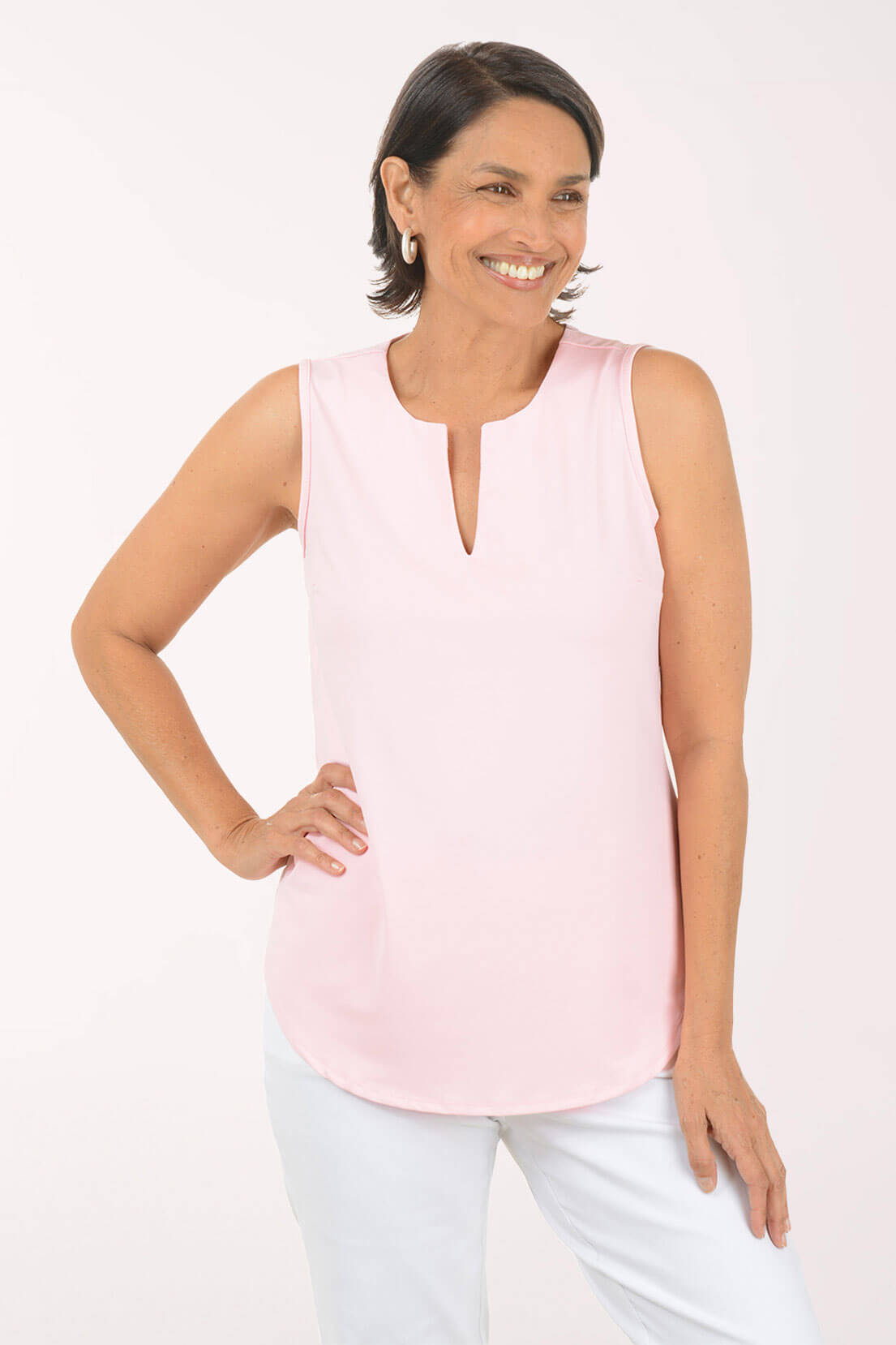 Woman wearing a light pink sleeveless top against a white background