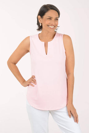 Woman wearing a light pink sleeveless top against a white background