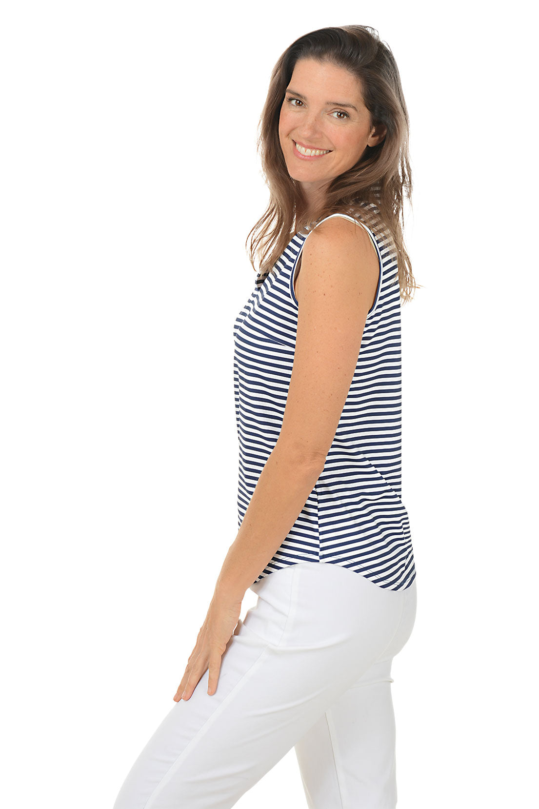 Woman wearing a sleeveless striped shirt and white pants on a white background. Side shot.