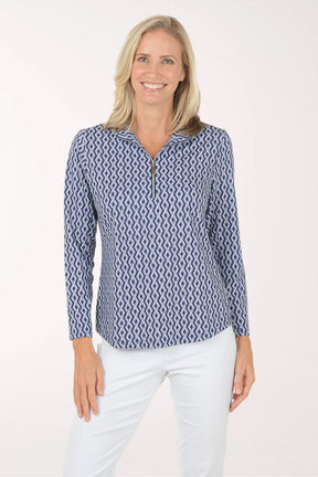 Woman wearing a blue patterned long-sleeve shirt and white pants on a white background
