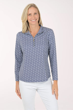 Woman wearing a blue patterned long-sleeve shirt and white pants on a white background
