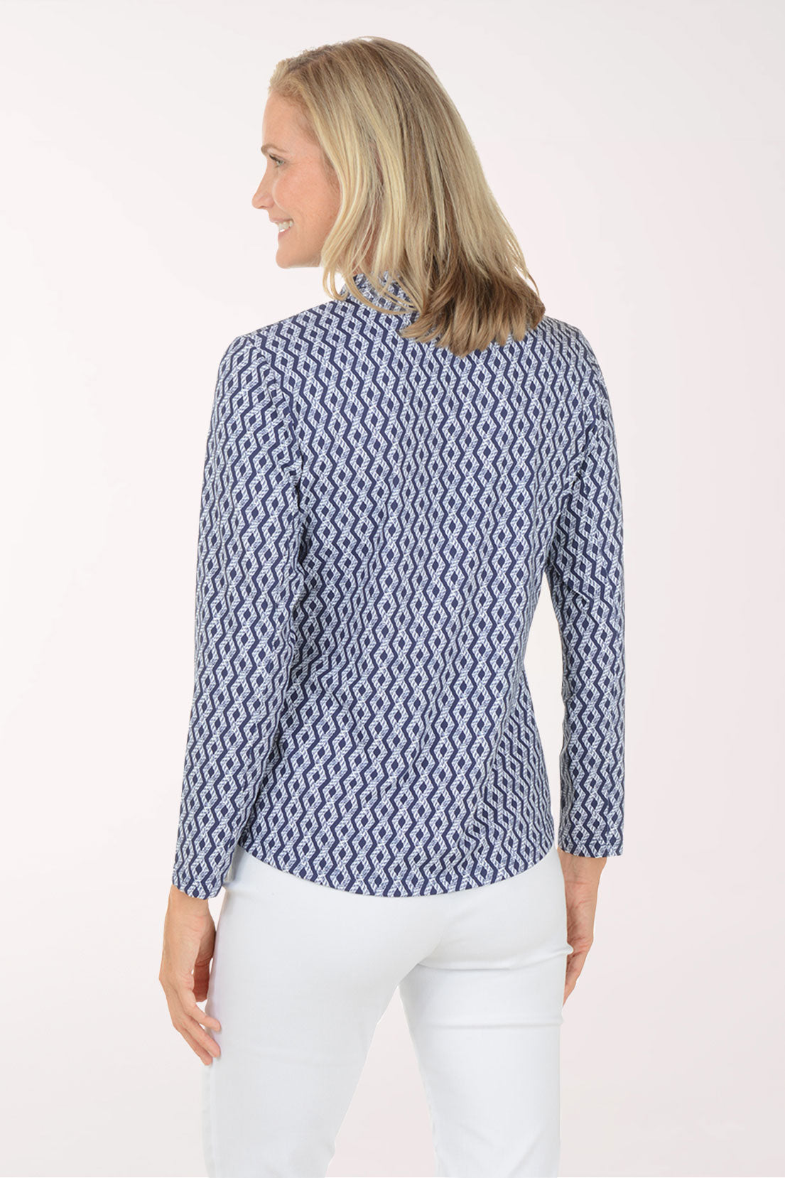 Woman wearing a blue patterned long-sleeve shirt and white pants on a white background