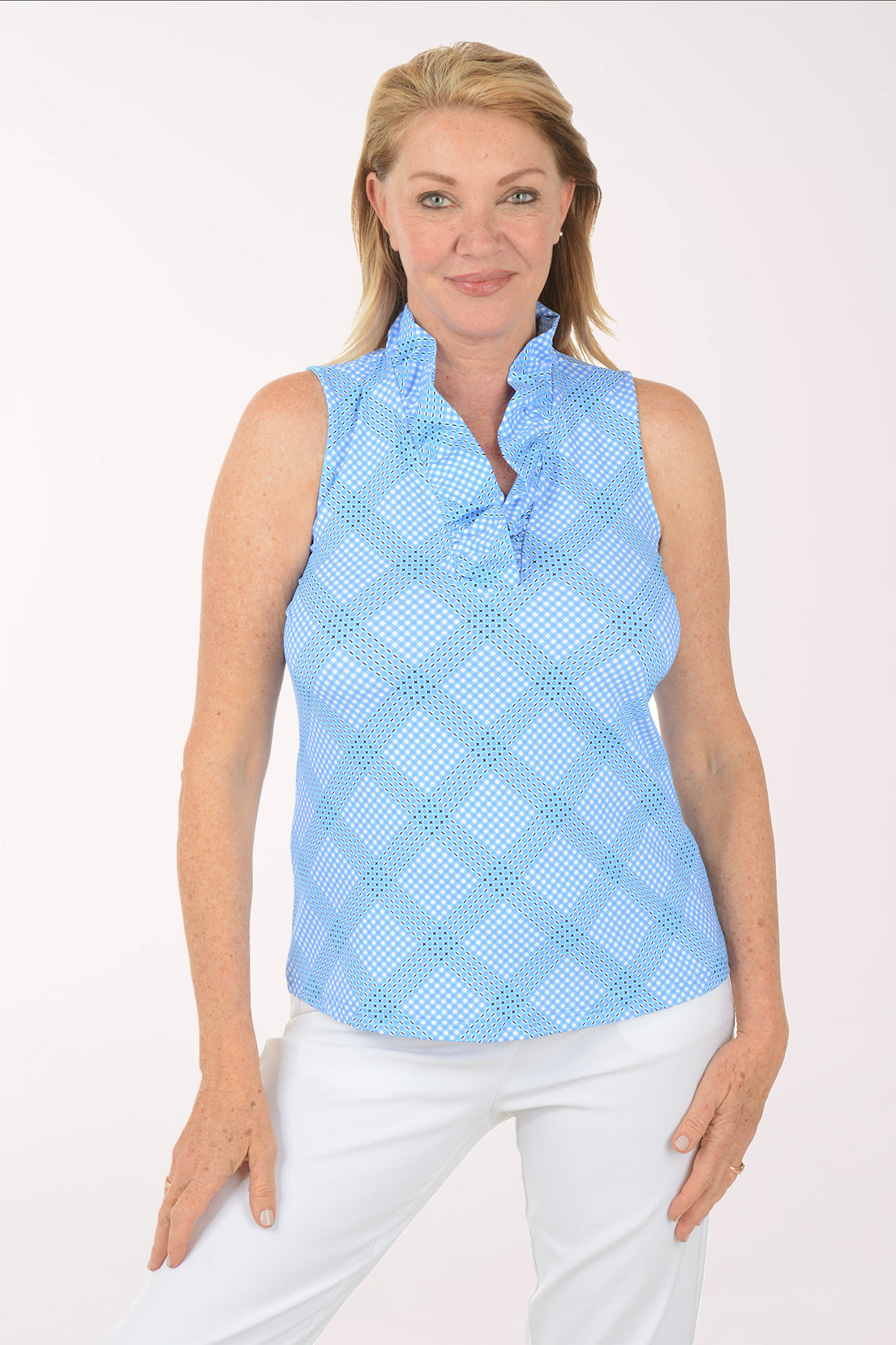 Woman wearing a light blue sleeveless checkered top and white pants on a white background